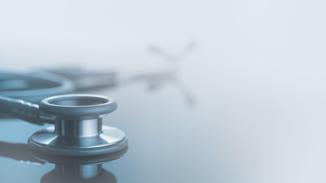 Medical background, Close up stethoscope on glass table with reflection and copy space, monotone, soft background.
