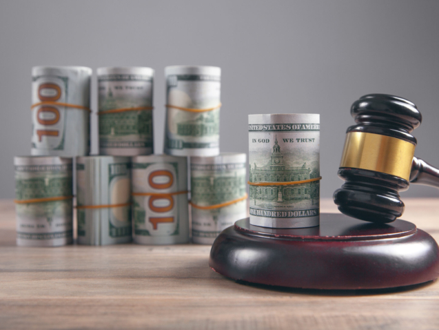 Judge gavel and money rolls on wooden table.